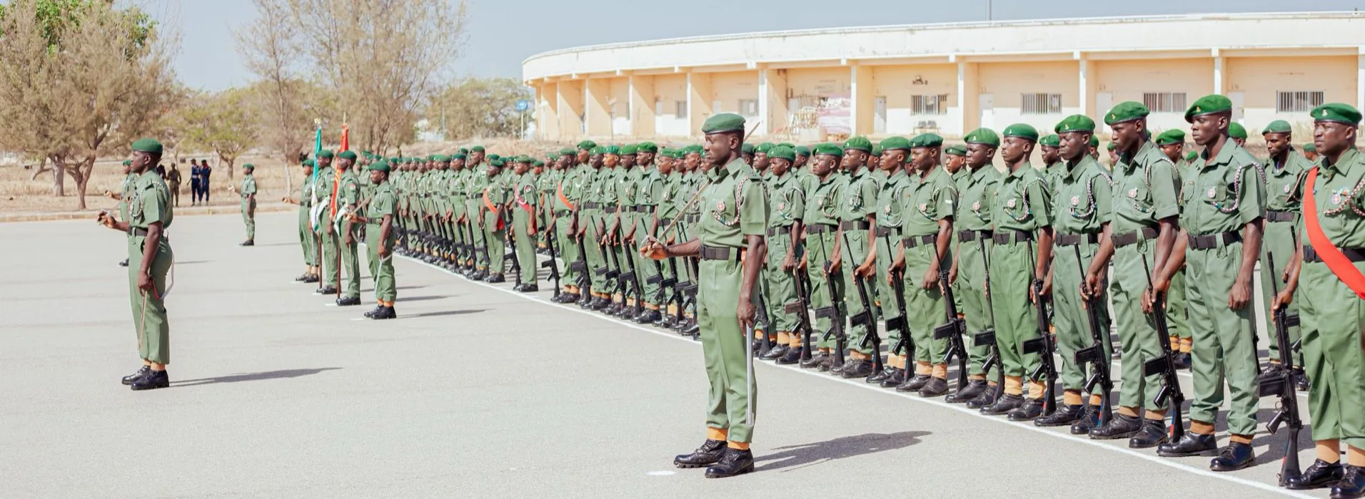Rows of young recruits in green fatigues and berets drawn up in formation on a parade ground