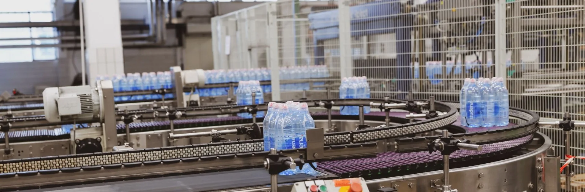 Bottled water moving along conveyor lines inside a modern bottling plant