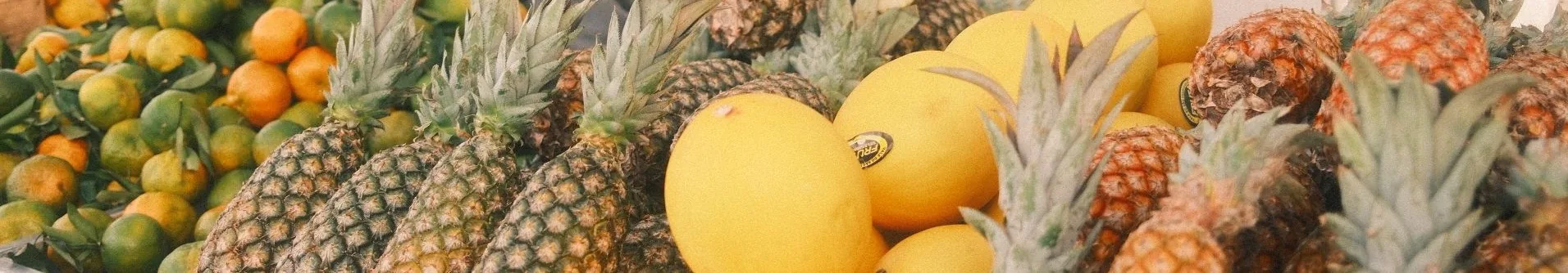 A market stall piled with pineapples, melons and citrus